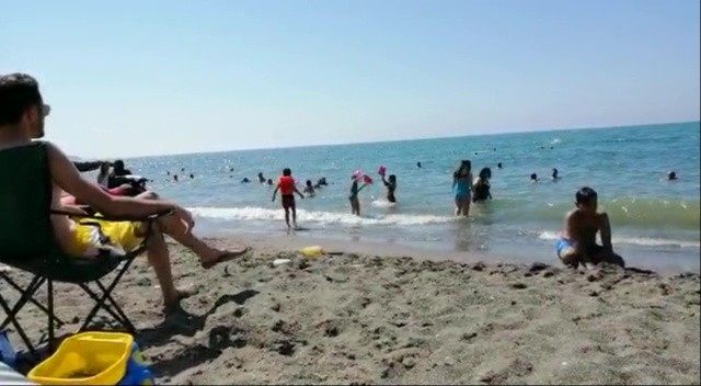 Çocuklar, kumsalın anne babalar denizin tadını çıkarıyor